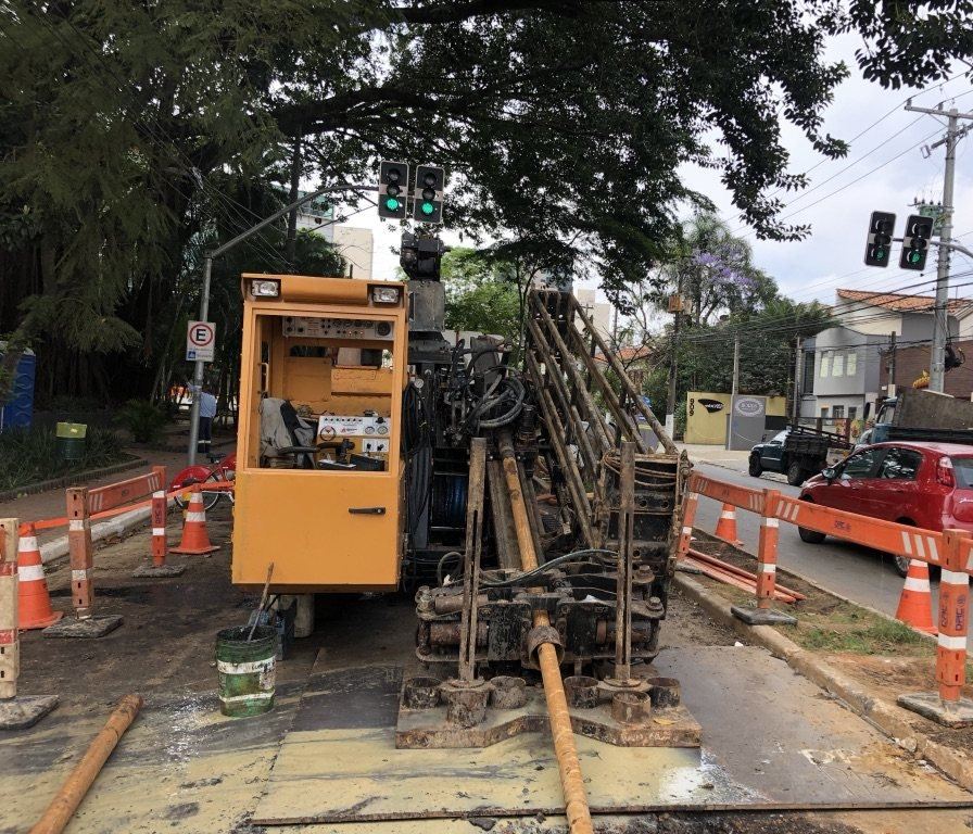 Perfuratriz direcional com cabine operando em cruzamento urbano para rede subterrânea de energia, com a via em funcionamento